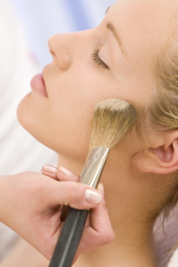 A beautiful young woman having her make up applied by a beautician